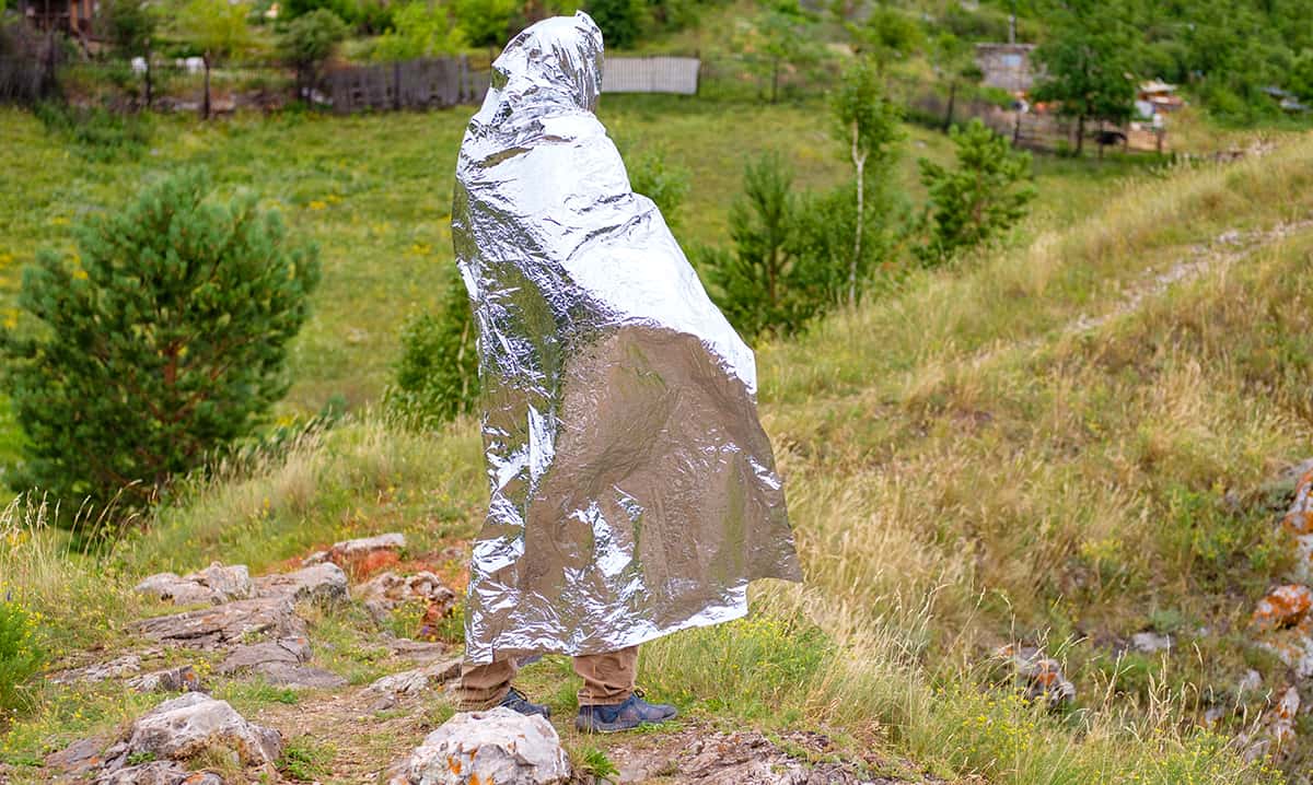 Hiker using a foil blanket to stay warm while outdoors