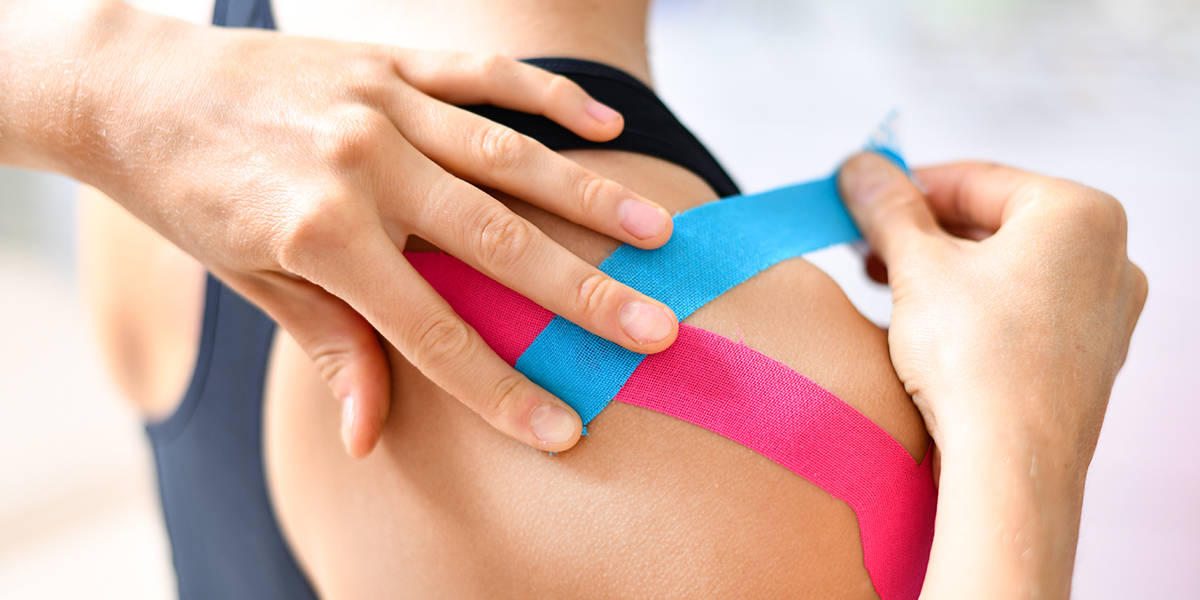 Kinesiology tape being applied to a woman’s shoulder